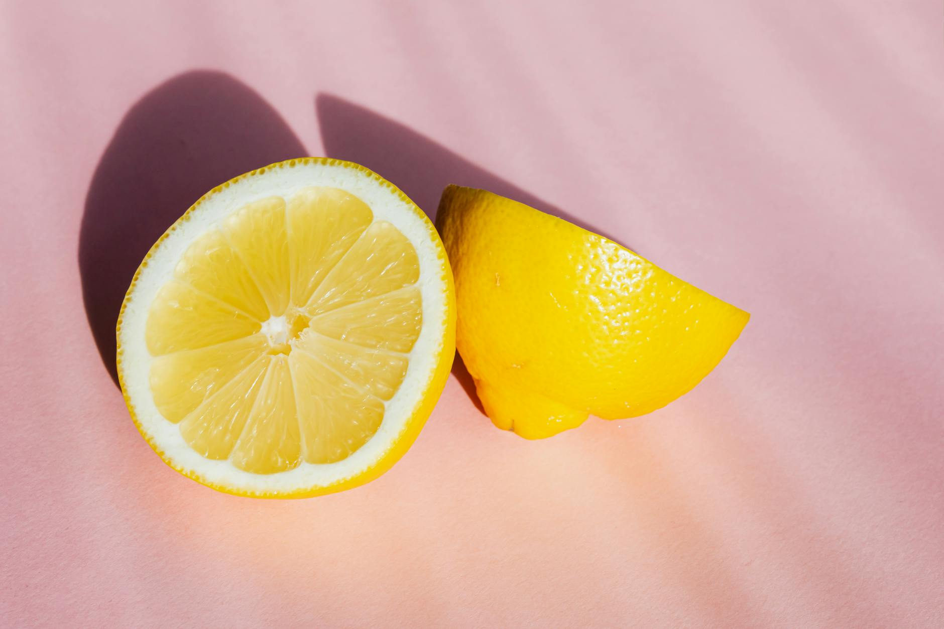 Fresh lemon halves on a pink background in sunlight, symbolizing renewed sensation and vitality
