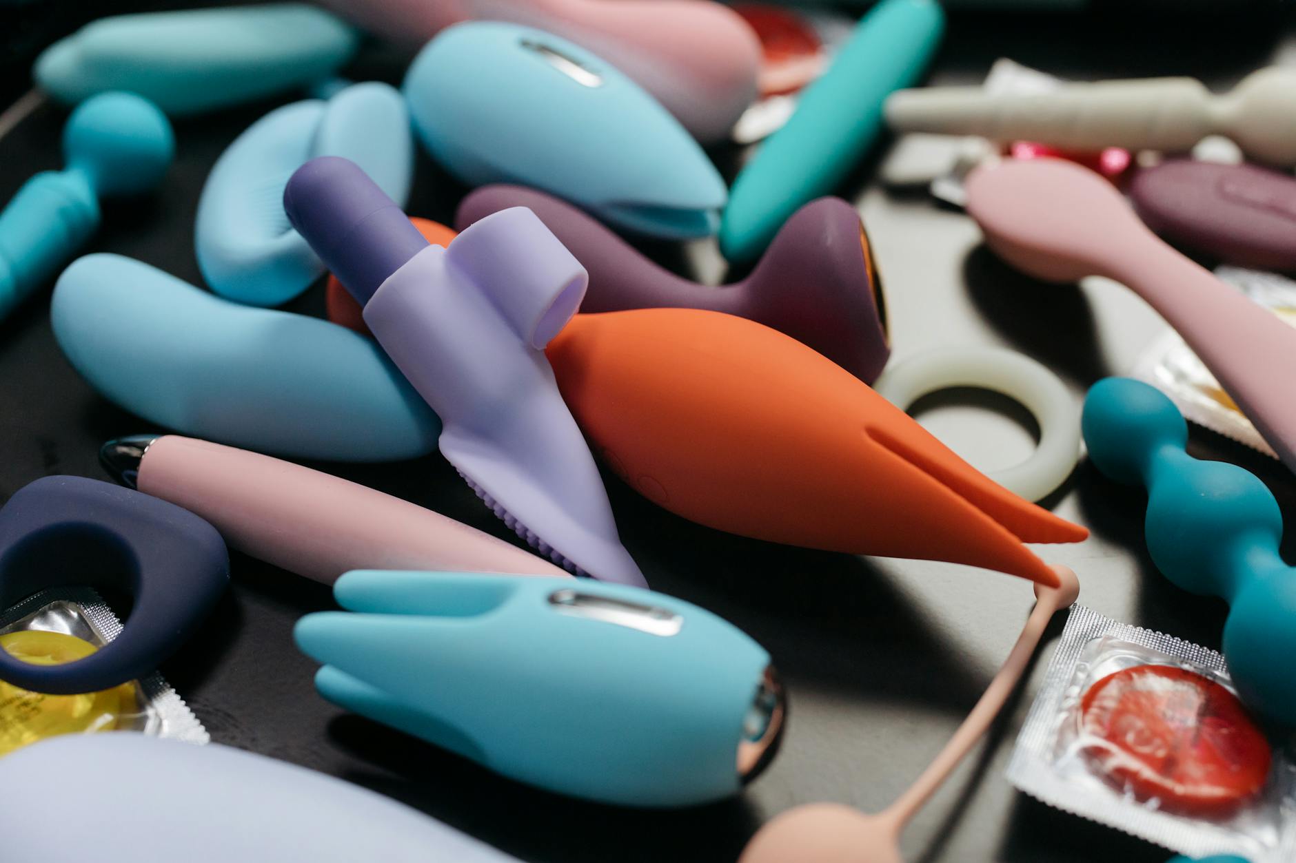 Person holding blue and pink vibrators thoughtfully, representing different approaches to pleasure and sensation.