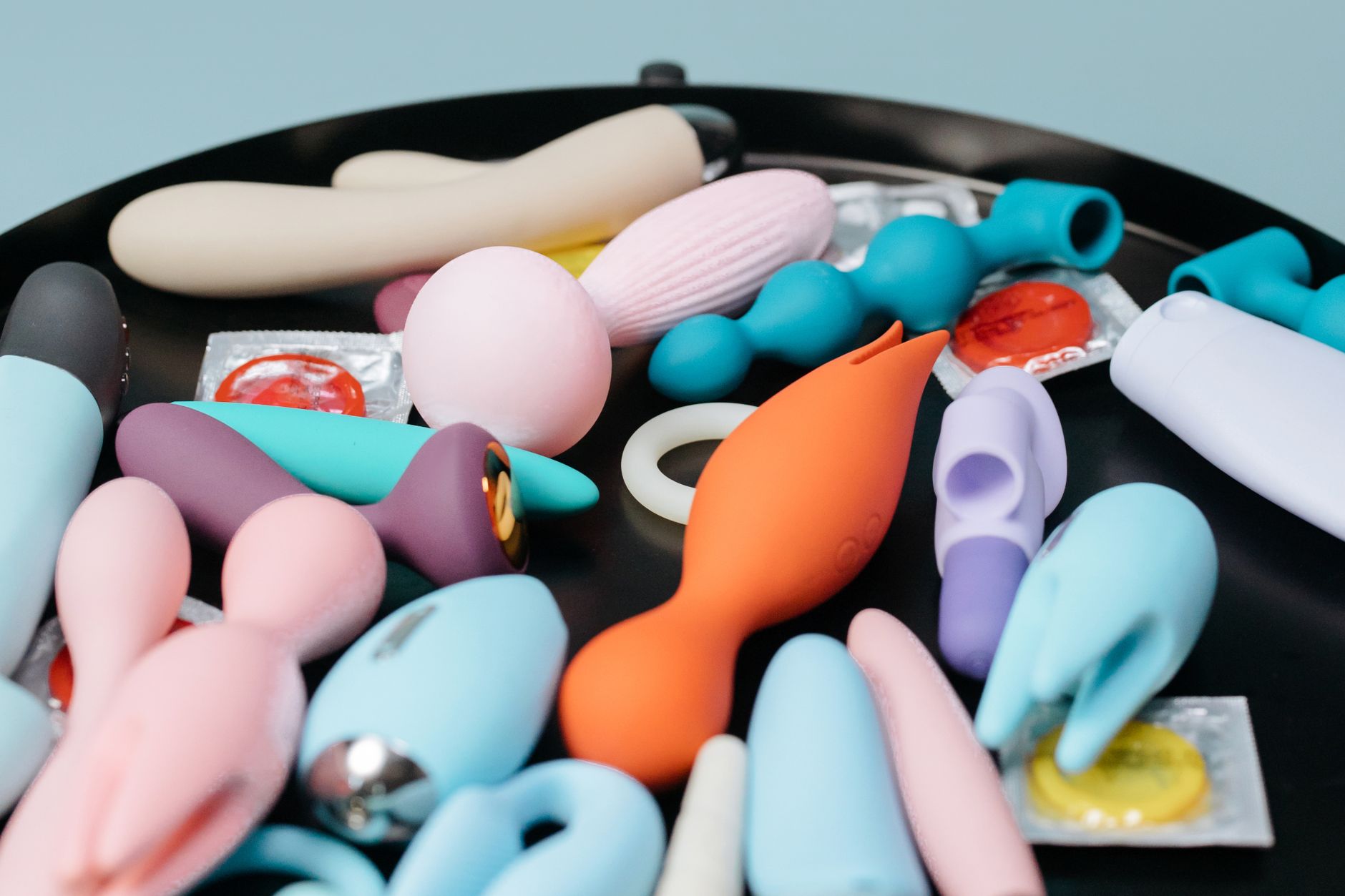 Various clitoral vibrators and intimate wellness tools arranged on a dark surface, representing diverse pleasure options during recovery.