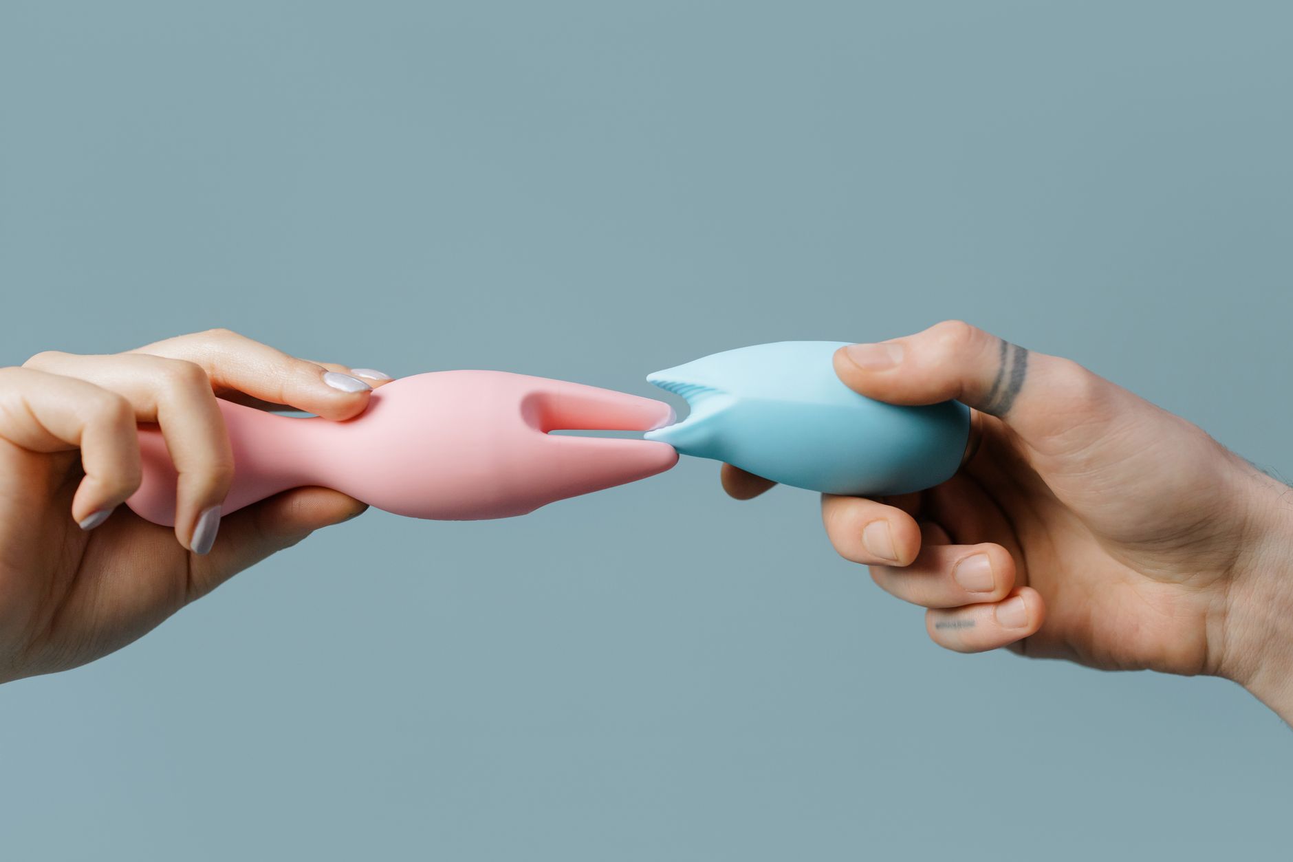 Hand holding an orange vibrator against a minimalist backdrop