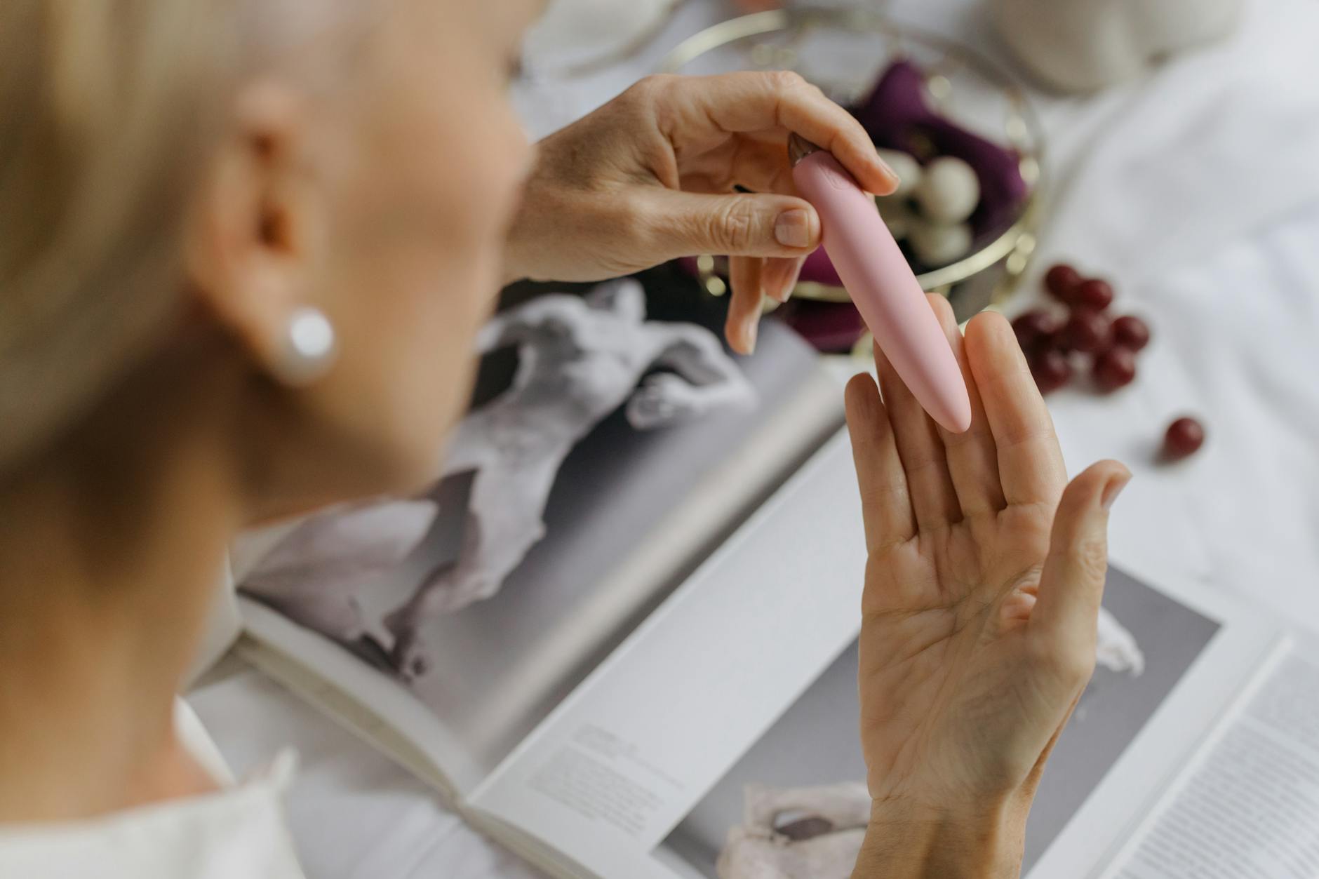 Woman holding vibrators with art books in background